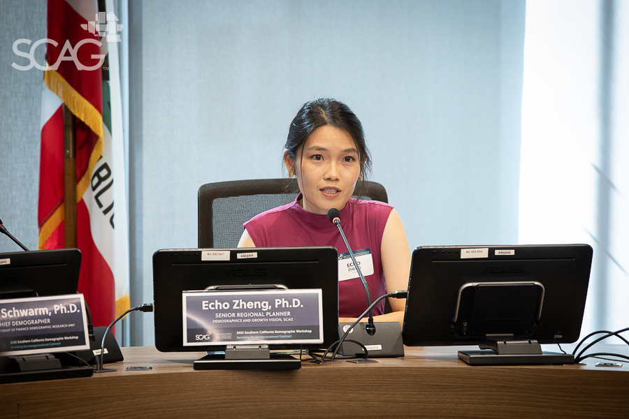 Woman speaking at a conference with multiple monitors on the table.